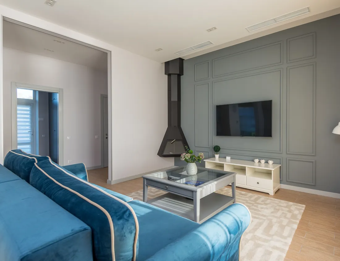 Living room with a blue couch and wall-mounted television, London