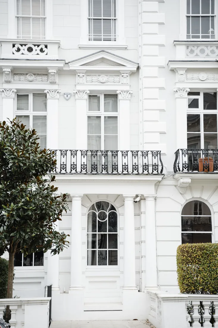 White stucco period townhouse with sash windows and a wrought-iron balcony, London